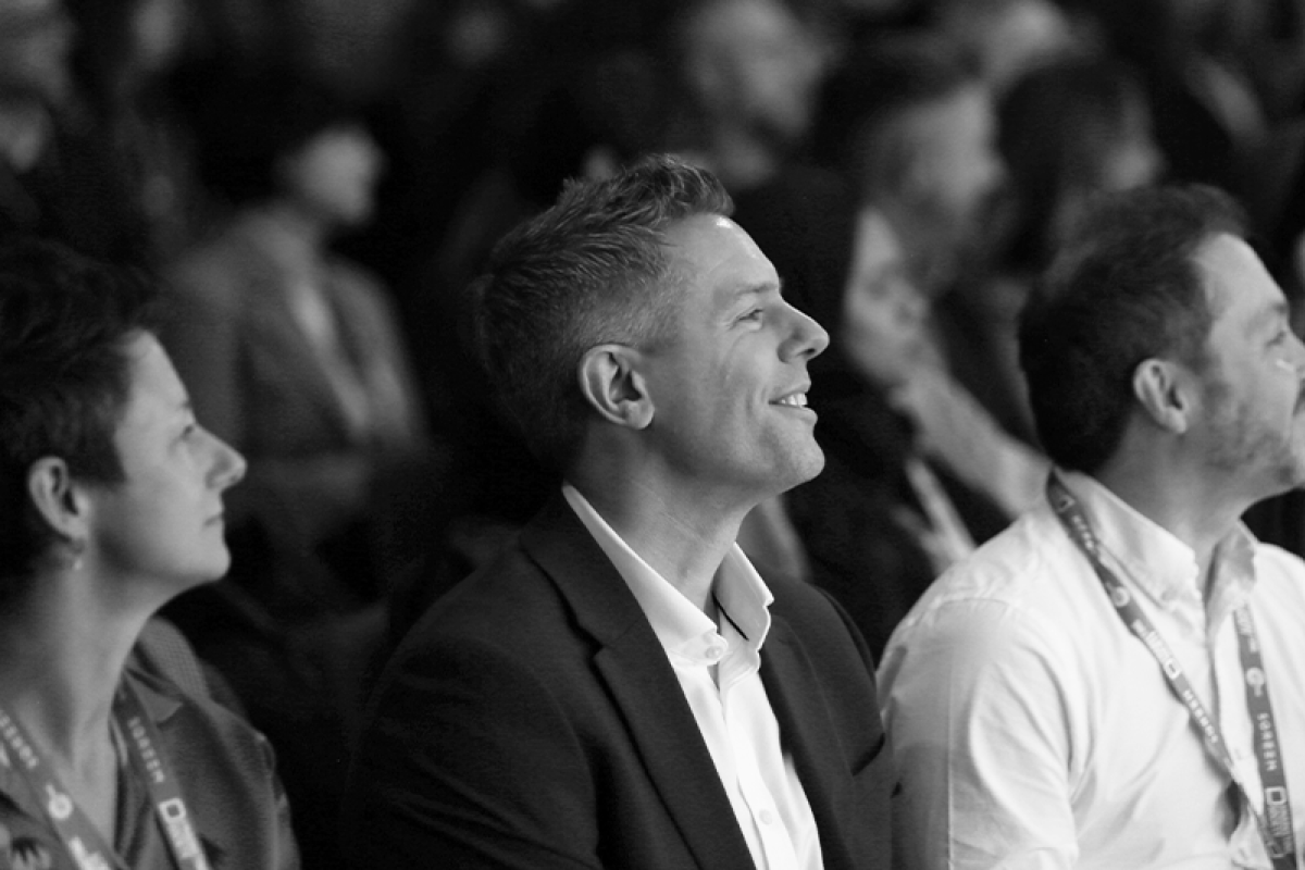 A conference of people, image focused on man smiling